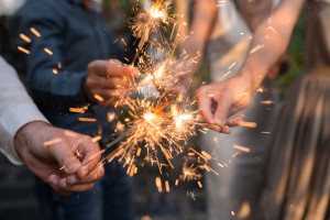 Hands of people holding Bengal light at the party